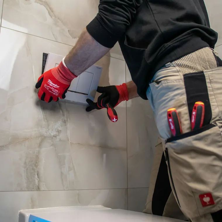 Gasfíter con guantes y herramientas trabajando en un baño